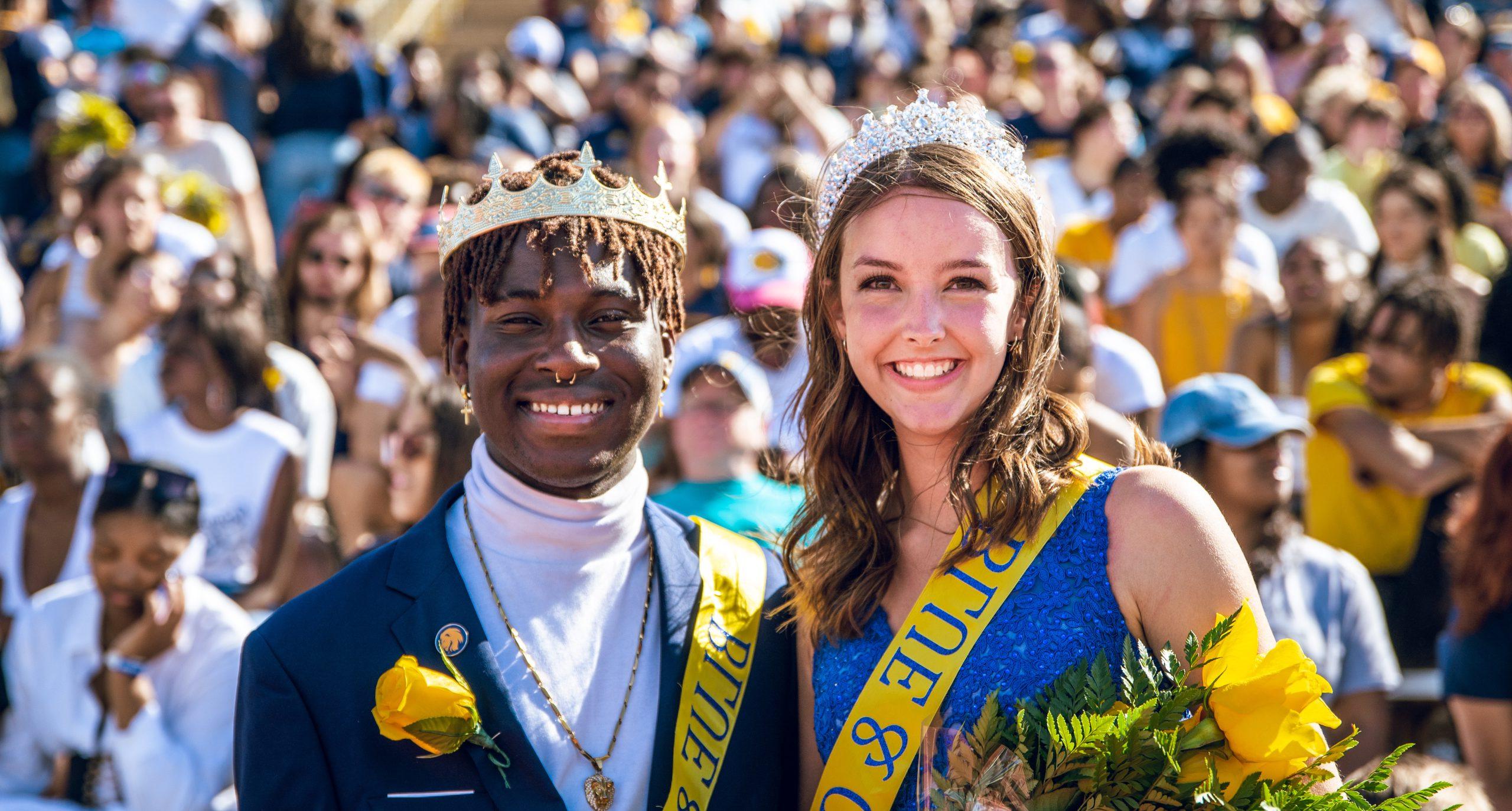 Two people in crowns and sashes pose for a photo